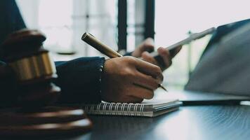 Business and lawyers discussing contract papers with brass scale on desk in office. Law, legal services, advice, justice and law concept picture with film grain effect video