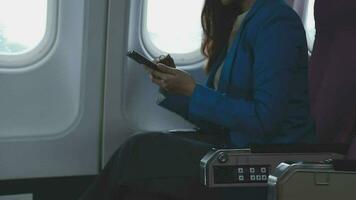 Traveling and technology. Flying at first class. Pretty young businees woman using smartphone while sitting in airplane. video