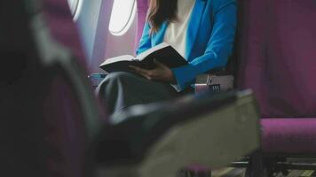 exitoso hembra libro editor leyendo literatura durante hora en avión antes de negocio reunión con escritor, confidente formalmente vestido mujer disfrutando internacional vuelo y ocio para novela video