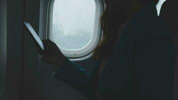 Traveling and technology. Flying at first class. Pretty young businees woman using smartphone while sitting in airplane. video