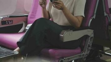 Businesswoman with short haircut sitting in airplane cabin and chatting online on smartphone while checking email on laptop computer with mock up area.Female traveler reading notification on cellular video