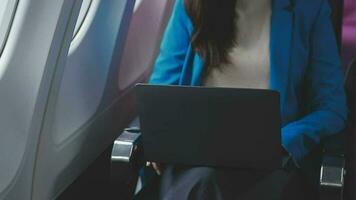 Successful beautiful young asian business woman sits in airplane cabinplane and works on digital tablet with stylus. Flying at first class. video