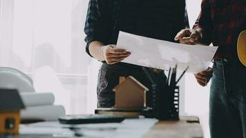 Image of team engineer checks construction blueprints on new project with engineering tools at desk in office. video