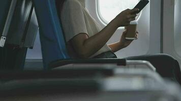retrato do uma bem sucedido ásia o negócio mulher ou fêmea empreendedor dentro formal terno dentro uma avião senta dentro uma o negócio classe assento e beber café durante voo, relaxar conceito video