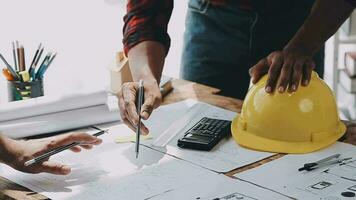 Image of team engineer checks construction blueprints on new project with engineering tools at desk in office. video