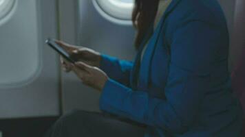 de viaje y tecnología. volador a primero clase. bonito joven businees mujer utilizando teléfono inteligente mientras sentado en avión. video