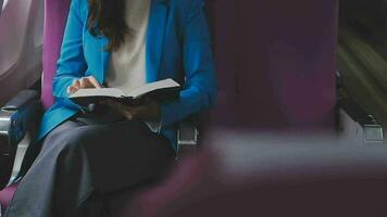 Successful female book editor reading literature during time in airplane before business meeting with writer, confident formally dressed woman enjoying international flight and leisure for novel video