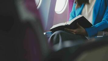 Successful female book editor reading literature during time in airplane before business meeting with writer, confident formally dressed woman enjoying international flight and leisure for novel video