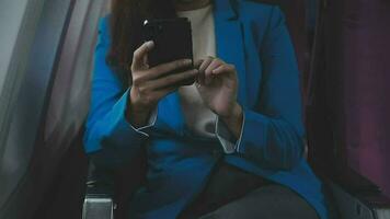 in viaggio e tecnologia. volante a primo classe. bella giovane imprenditori donna utilizzando smartphone mentre seduta nel aereo. video