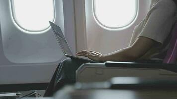 mulher usando computador portátil enquanto é sentado dentro avião perto janela. video