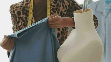caucasico femmina moda progettista lavori nel studio di idea disegno schizzi con digitale tavoletta e colorato tessuto per un' vestito design collezione, scegliere capi di abbigliamento colori per sartoria e progettazione video