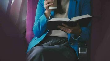 bem sucedido fêmea livro editor lendo literatura durante Tempo dentro avião antes o negócio encontro com escritor, confiante formalmente vestido mulher desfrutando internacional voar e lazer para romance video