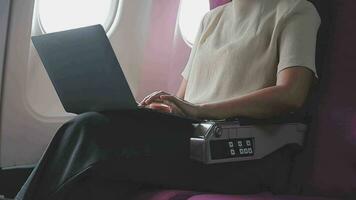 Woman using laptop while is sitting in plane near window. video