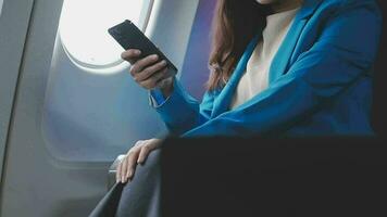 Traveling and technology. Flying at first class. Pretty young businees woman using smartphone while sitting in airplane. video