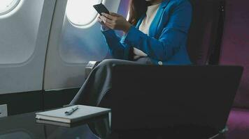 viajando e tecnologia. vôo às primeiro aula. bonita jovem empresários mulher usando Smartphone enquanto sentado dentro avião. video