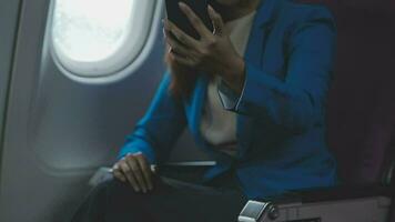 Traveling and technology. Flying at first class. Pretty young businees woman using smartphone while sitting in airplane. video