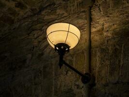 Old ancient lamp on the wall of a prison background, gloomy light photo