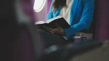 bem sucedido fêmea livro editor lendo literatura durante Tempo dentro avião antes o negócio encontro com escritor, confiante formalmente vestido mulher desfrutando internacional voar e lazer para romance video