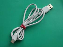 White usb cable, isolated on green background, computer peripherals connector or smartphone recharge supply photo