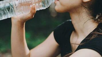 Drinking water, fitness and exercise woman after sports run and training in nature. Workout, hiking and walking challenge with a bottle of a female runner in summer ready for running for health video