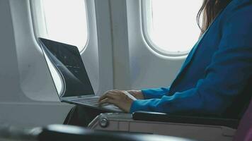 framgångsrik skön ung asiatisk företag kvinna sitter i flygplan kabinflygplan och Arbetar på digital läsplatta med nål. flygande på först klass. video