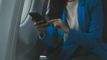 en voyageant et technologie. en volant à premier classe. jolie Jeune entreprises femme en utilisant téléphone intelligent tandis que séance dans avion. video