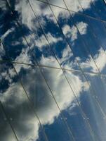 Reflection of clouds and blue sky in the glass wall of a modern business center photo