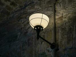 Old ancient lamp on the wall of a prison background, gloomy light photo