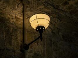 Old ancient lamp on the wall of a prison background, gloomy light photo