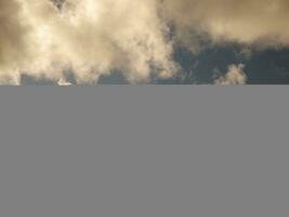 Fluffy clouds over sunset sky. Fluffy cumulus cloud shape photo, gloomy cloudscape background photo