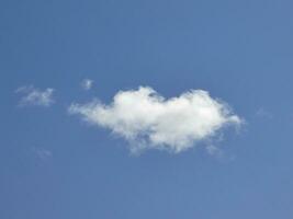 Single white cloud over blue sky background. Fluffy cumulus cloud shape photo