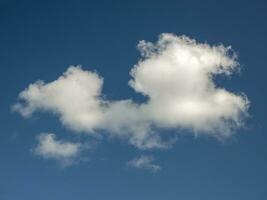 Single white cloud over blue sky background. Fluffy cumulus cloud shape photo