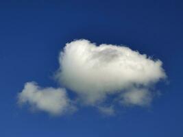 Single white cloud over blue sky background. Fluffy cumulus cloud shape photo