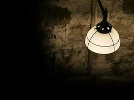 Old ancient lamp on the wall of a prison background, gloomy light photo