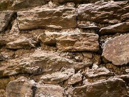 Old stone wall pattern close view background, ancient bricks surface. Natural rock wall photo