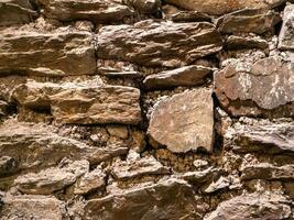 Old stone wall pattern close view background, ancient bricks surface. Natural rock wall photo