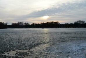 Sunset over frozen winter lake photo