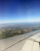 Airplane wing and land far under the plane photo