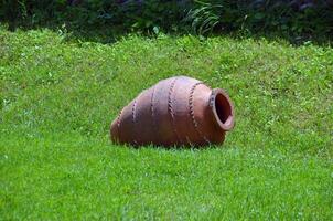 Wine jar laying on green grass photo