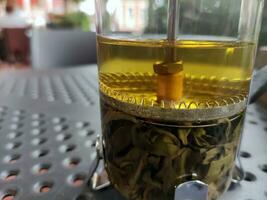 Green tea in a transparent glass kettle photo
