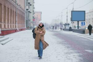A girl in a long coat walks through the city in cold weather photo