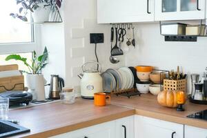 Decor of the white classic kitchen with pumpkins for Halloween and harvest. Autumn mood in the home interior, modern loft style. photo