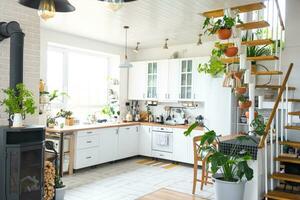 The general plan of a light white modern rustic kitchen with a modular metal staircase decorated with potted plants. Interior of a house with homeplants photo