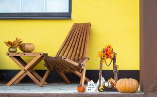 Autumn decor on porch of yellow house outside of pumpkin, lantern, garlands and figure of home and key. Halloween party, autumn mood, Harvest festival, real estate, insurance, mortgage photo