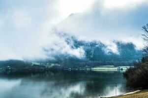 Humid and foggy morning on the cold Alpian lake between the mountains photo