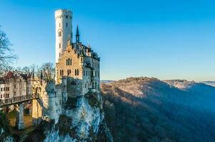 Ancient castle on the rock with a deep forest and blue sky on the background photo