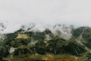 High mountain covered with deep white clouds with small spots of sunrays photo