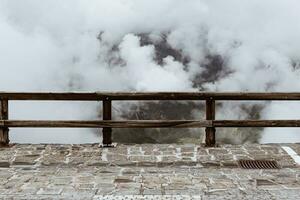 Wooden fence on top of the mountain with white clouds on the background photo