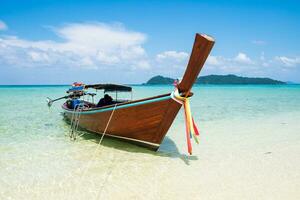Long tail wooden boat anchor with csytal sea white sand photo