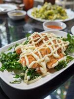 Lemon fried chicken topped with mayonnaise decorate white plate and vegetable photo